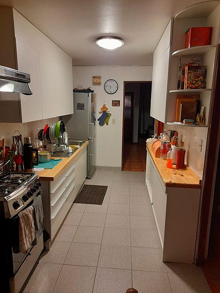 Vista panorámica cocina integral renovada aprovechando largo total del muro, muebles a medida melamina Santiago 2022